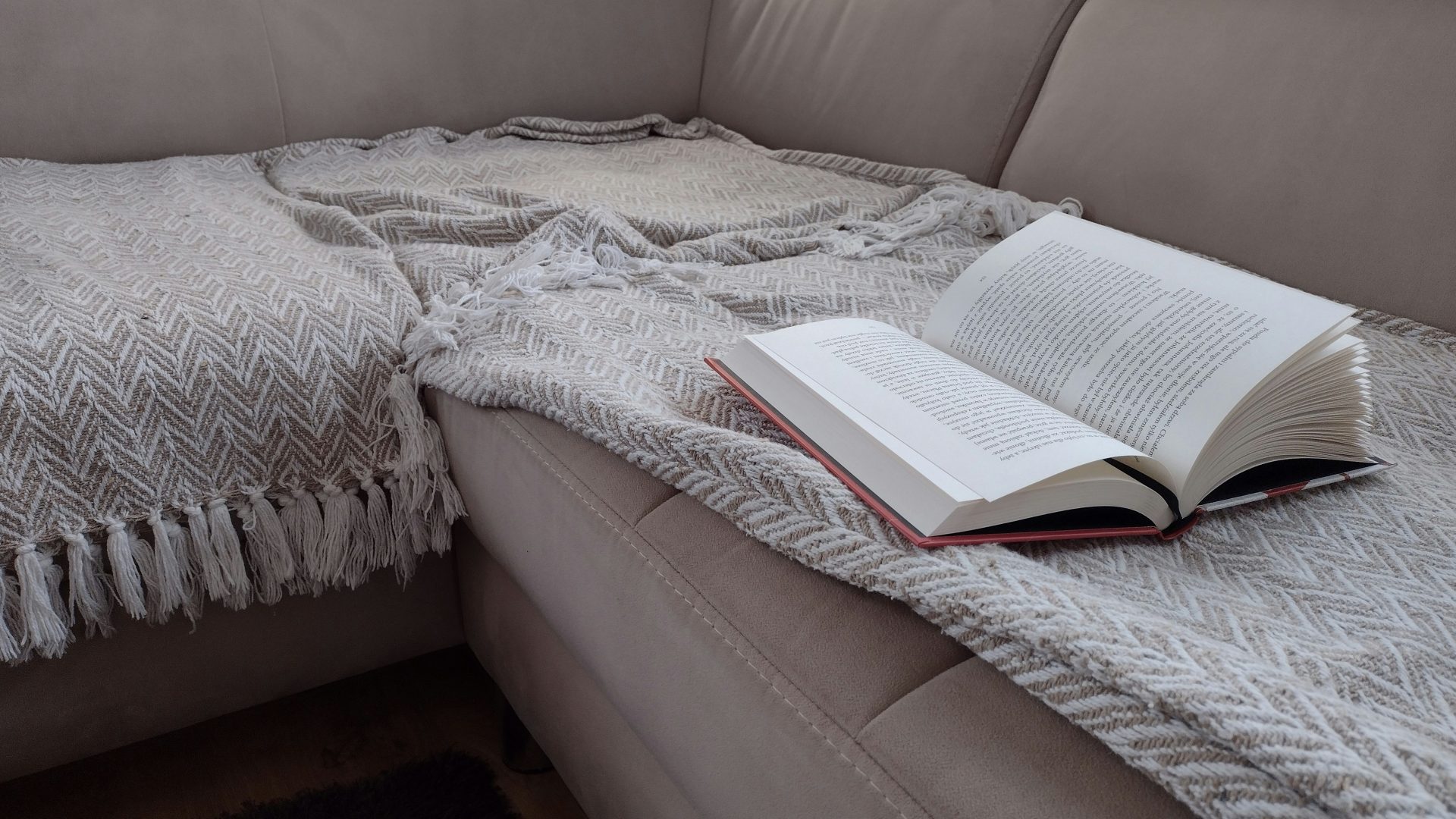 An open book is laying on a couch